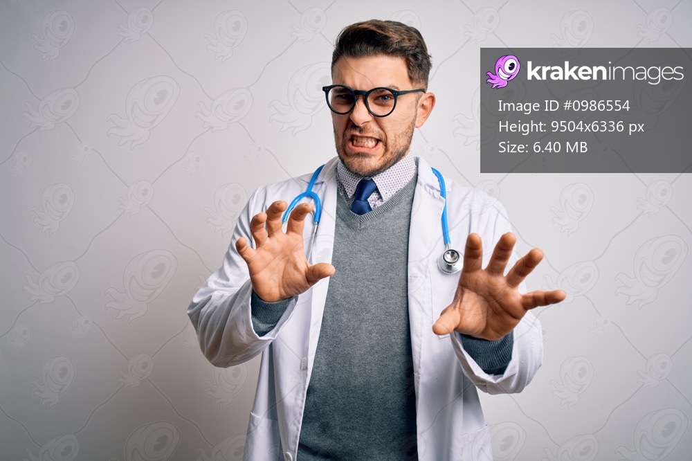 Young doctor man with blue eyes wearing medical coat and stethoscope over isolated background smiling funny doing claw gesture as cat, aggressive and sexy expression