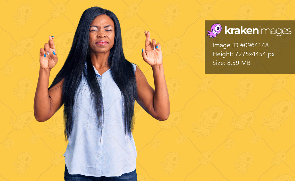 Young african american woman wearing casual clothes gesturing finger crossed smiling with hope and eyes closed. luck and superstitious concept. 