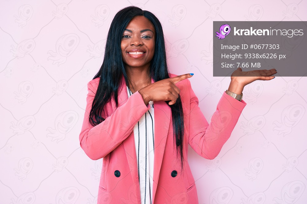 Young african american woman wearing business clothes amazed and smiling to the camera while presenting with hand and pointing with finger. 