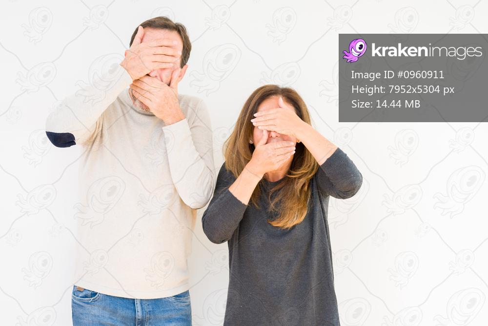 Beautiful middle age couple in love over isolated background Covering eyes and mouth with hands, surprised and shocked. Hiding emotion