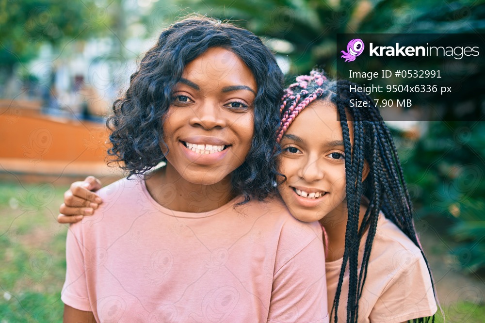 Beautiful african american mother and daughter smiling happy and hugging. Standing with smile on face standing at the park.
