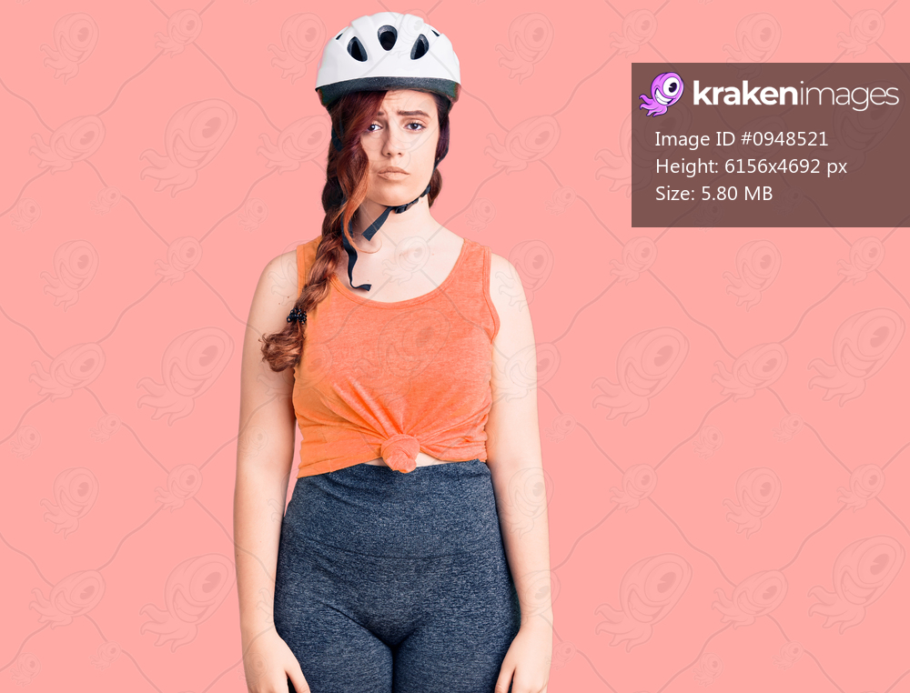 Young beautiful woman wearing bike helmet with serious expression on face. simple and natural looking at the camera. 