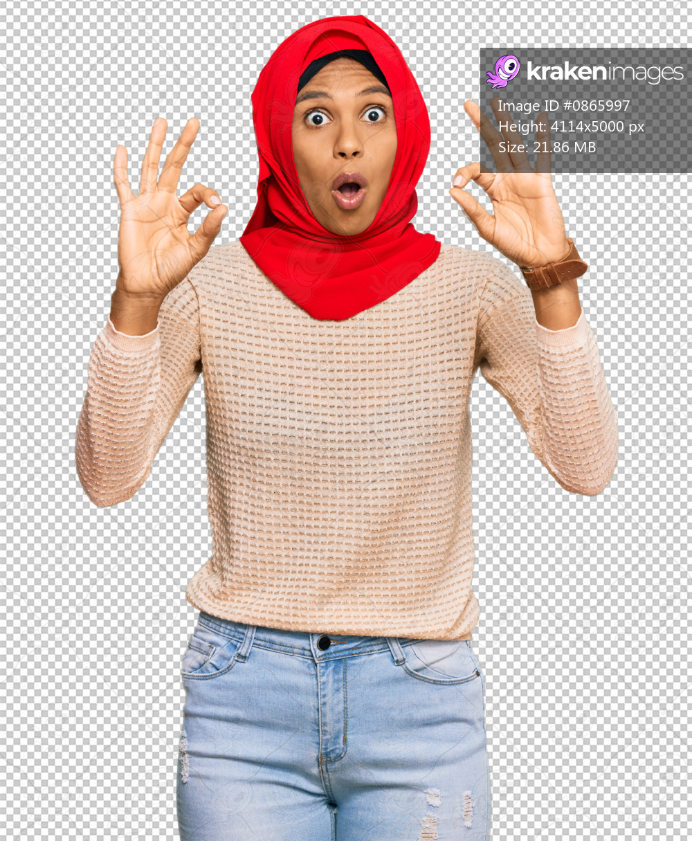 Young african american woman wearing traditional islamic hijab scarf looking surprised and shocked doing ok approval symbol with fingers. crazy expression