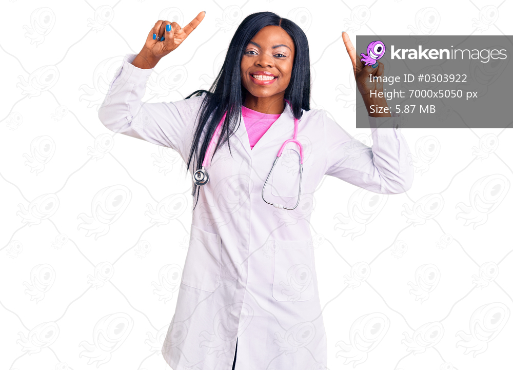 Young african american woman wearing doctor stethoscope smiling amazed and surprised and pointing up with fingers and raised arms. 