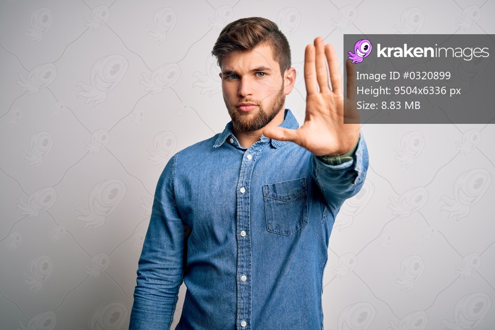 Young handsome blond man with beard and blue eyes wearing casual denim shirt doing stop sing with palm of the hand. Warning expression with negative and serious gesture on the face.