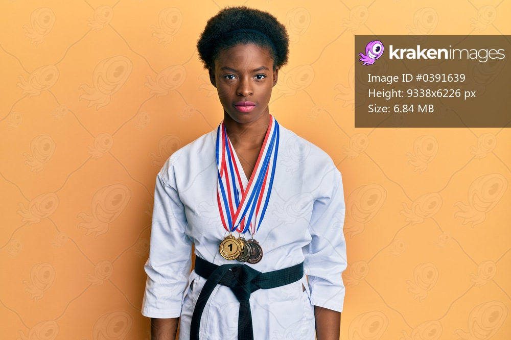 Young african american girl wearing karate kimono and black belt with serious expression on face. simple and natural looking at the camera. 
