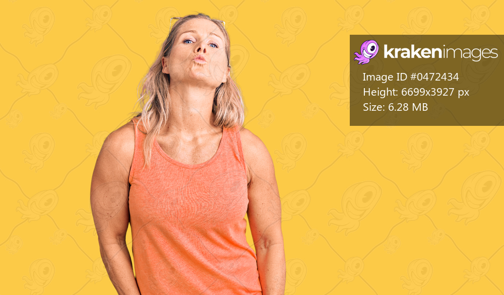 Middle age fit blonde woman wearing casual summer clothes and sunglasses looking at the camera blowing a kiss on air being lovely and sexy. love expression. 