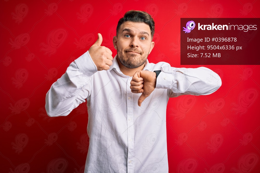 Young business man with blue eyes wearing elegant shirt standing over red isolated background Doing thumbs up and down, disagreement and agreement expression. Crazy conflict