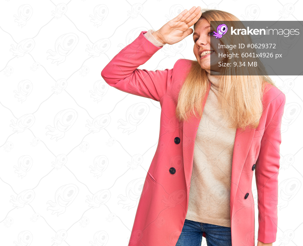 Young beautiful blonde woman wearing elegant clothes very happy and smiling looking far away with hand over head. searching concept. 