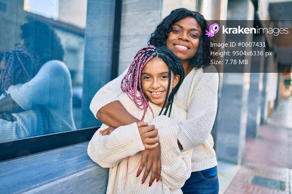 Beautiful african american mother and daughter smiling happy and hugging. Standing with smile on face standing at the city.