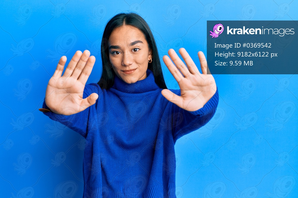 Young asian woman wearing casual winter sweater doing frame using hands palms and fingers, camera perspective 