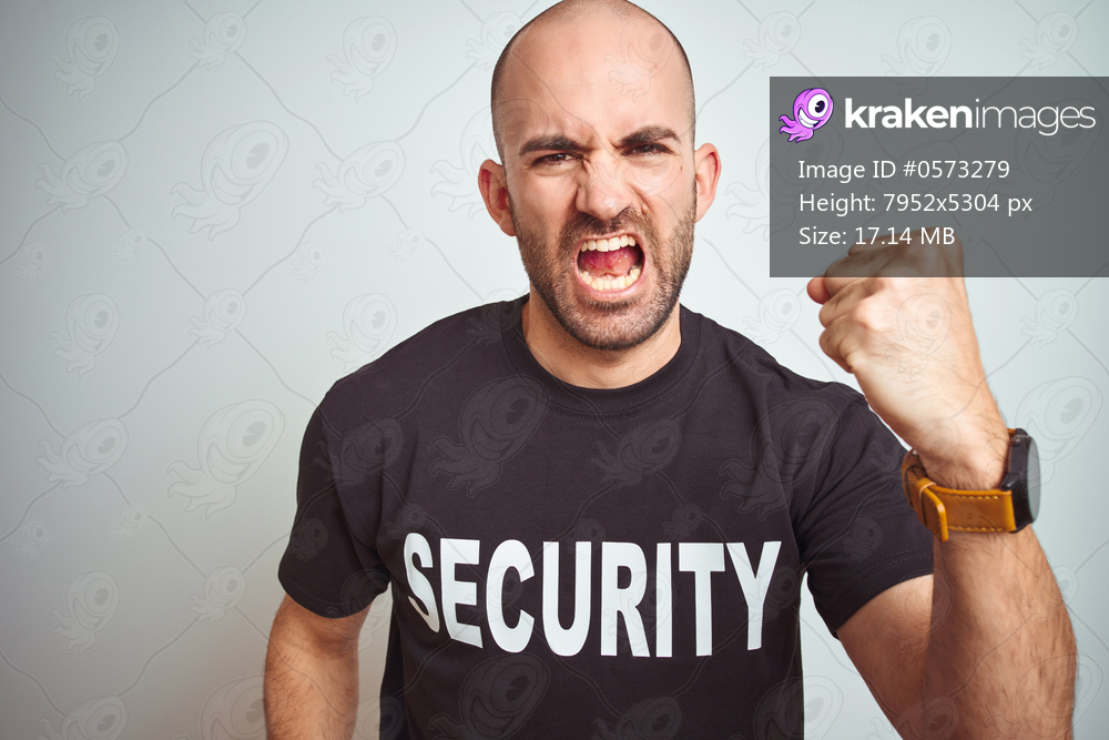 Young safeguard man wearing security uniform over isolated background angry and mad raising fist frustrated and furious while shouting with anger. Rage and aggressive concept.