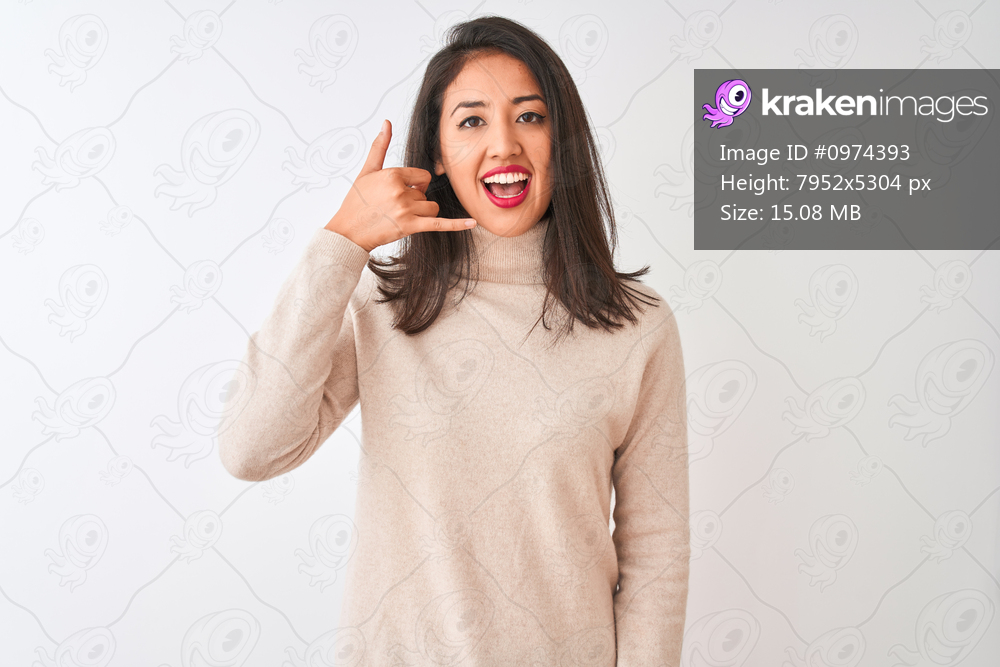 Beautiful chinese woman wearing turtleneck sweater standing over isolated white background smiling doing phone gesture with hand and fingers like talking on the telephone. Communicating concepts.