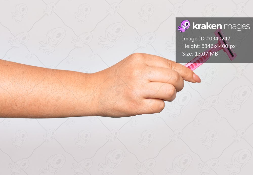 Hand of caucasian young woman holding pink razor over isolated white background