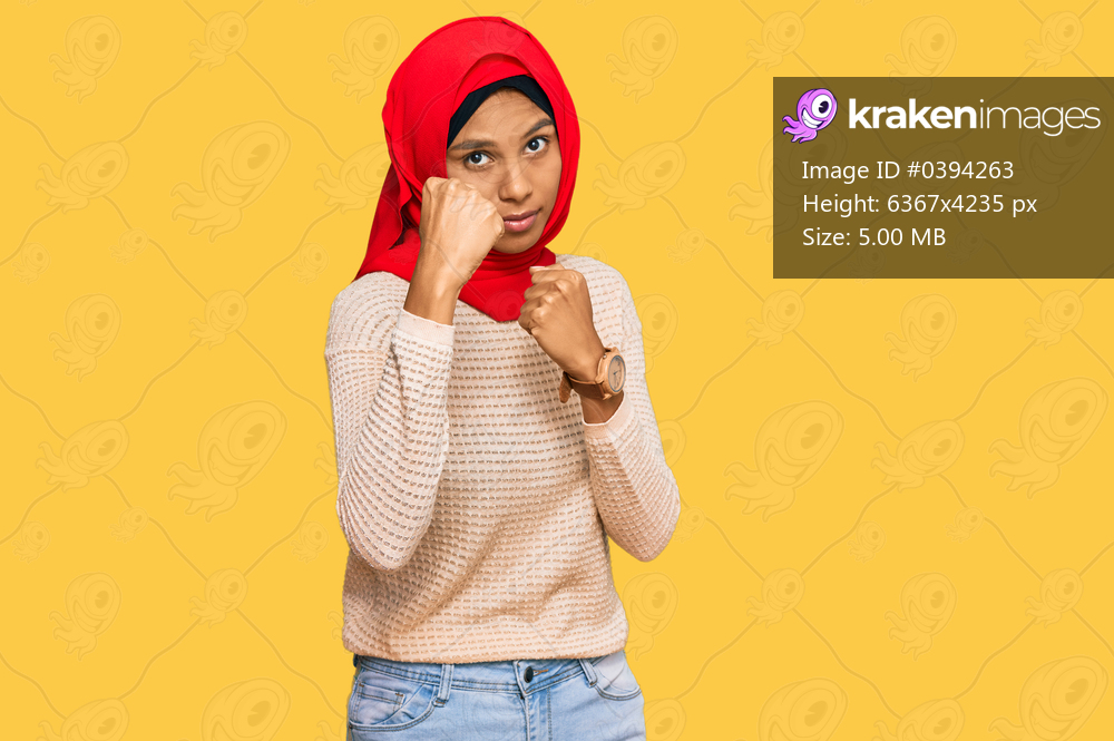 Young african american woman wearing traditional islamic hijab scarf ready to fight with fist defense gesture, angry and upset face, afraid of problem 