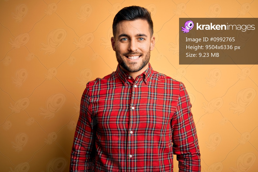 Young handsome man wearing casual shirt standing over isolated yellow background with a happy and cool smile on face. Lucky person.