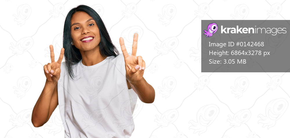 Young african american woman wearing casual clothes smiling looking to the camera showing fingers doing victory sign. number two. 