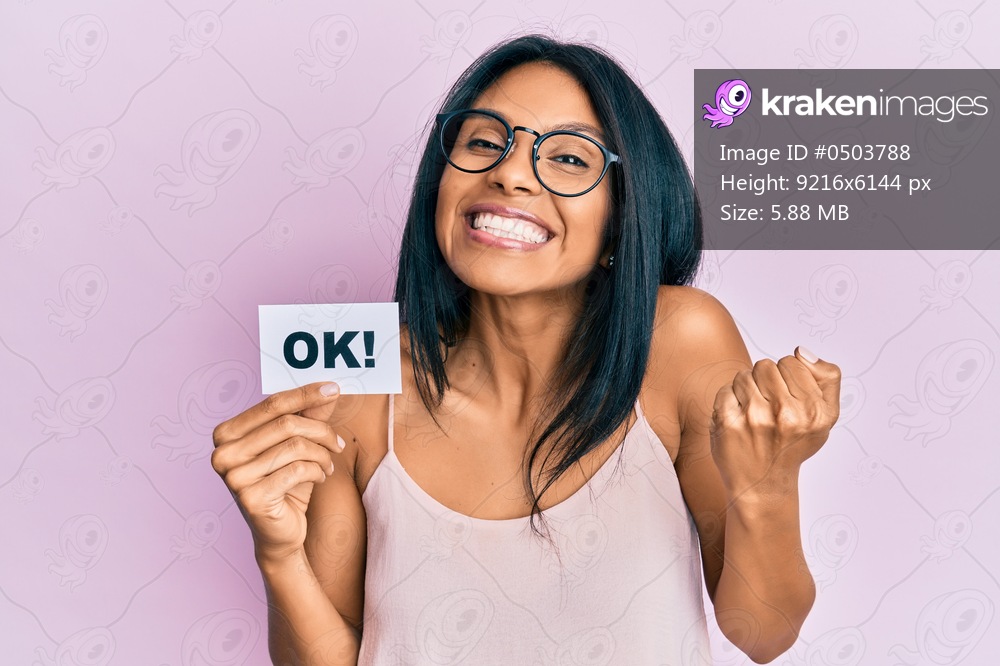 Young african american woman holding ok message paper screaming proud, celebrating victory and success very excited with raised arm 