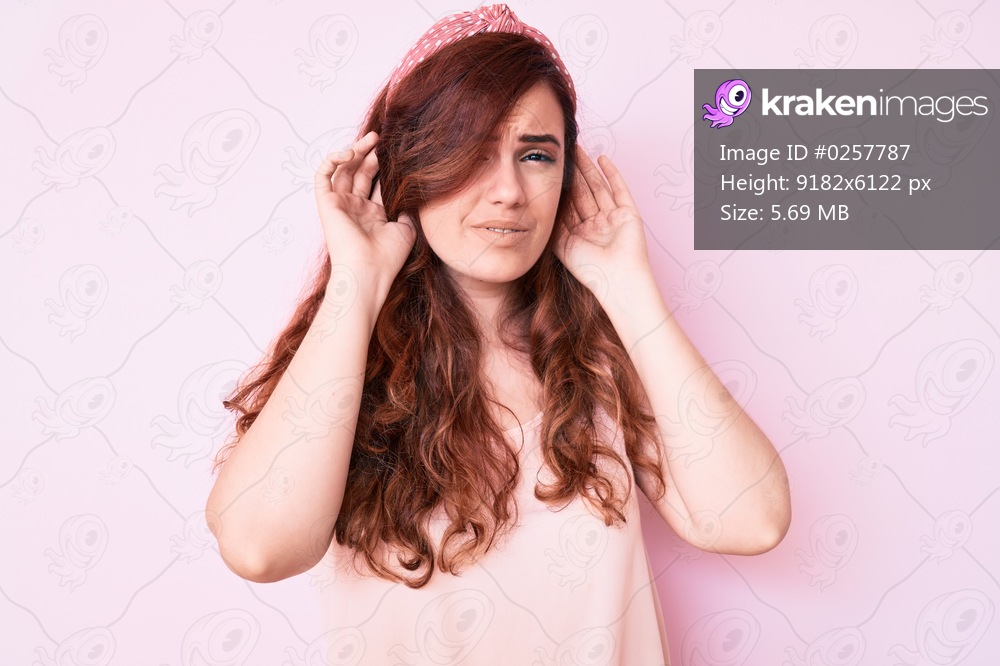 Young beautiful woman wearing casual clothes trying to hear both hands on ear gesture, curious for gossip. hearing problem, deaf 
