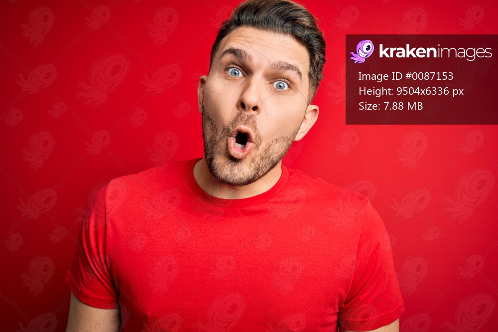 Young man with blue eyes wearing casual t-shirt over red isolated background afraid and shocked with surprise expression, fear and excited face.
