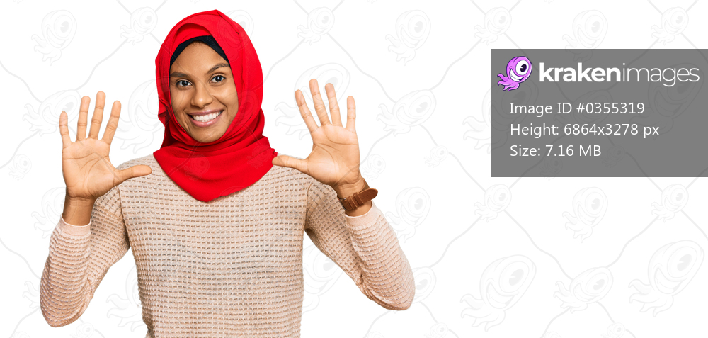 Young african american woman wearing traditional islamic hijab scarf showing and pointing up with fingers number ten while smiling confident and happy. 