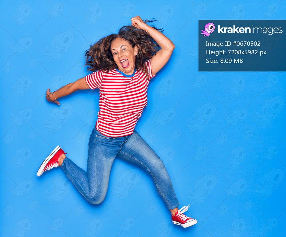 Middle age beautiful hispanic woman wearing casual clothes smiling happy. Jumping with smile on face over isolated blue background