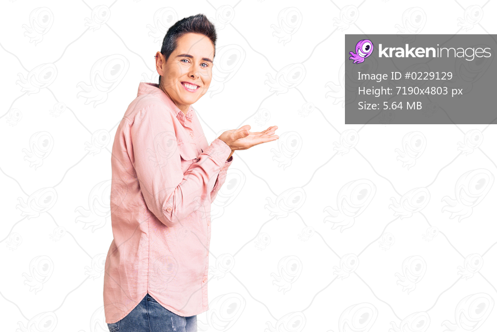 Young woman with short hair wearing casual clothes pointing aside with hands open palms showing copy space, presenting advertisement smiling excited happy 