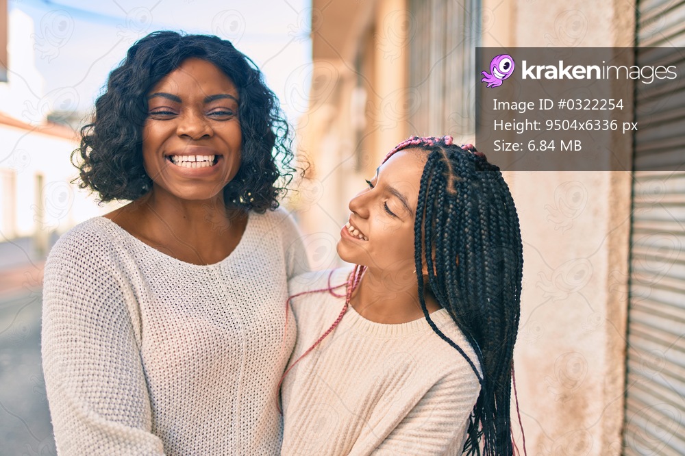 Beautiful african american mother and daughter smiling happy and hugging. Standing with smile on face standing at the city.