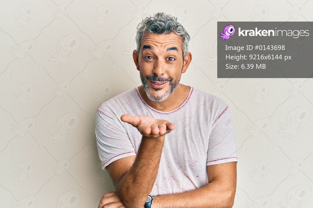Middle age grey-haired man wearing casual clothes looking at the camera blowing a kiss with hand on air being lovely and sexy. love expression. 