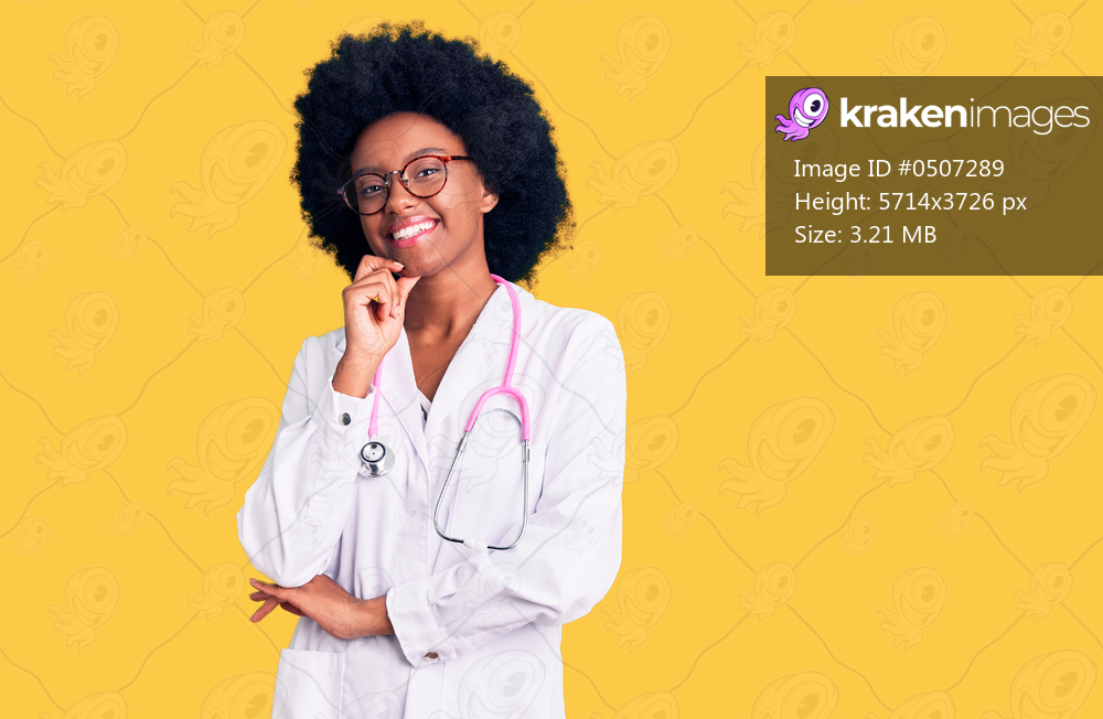 Young african american woman wearing doctor coat and stethoscope looking confident at the camera smiling with crossed arms and hand raised on chin. thinking positive. 