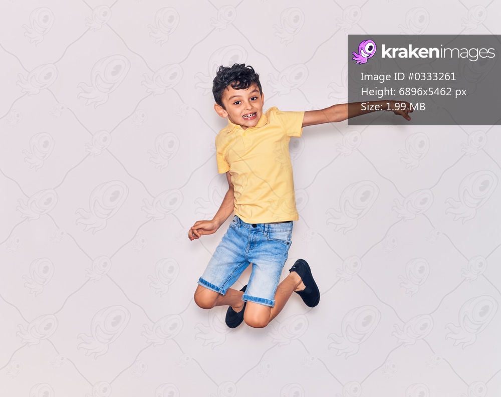 Adorable kid wearing casual clothes jumping over isolated white background