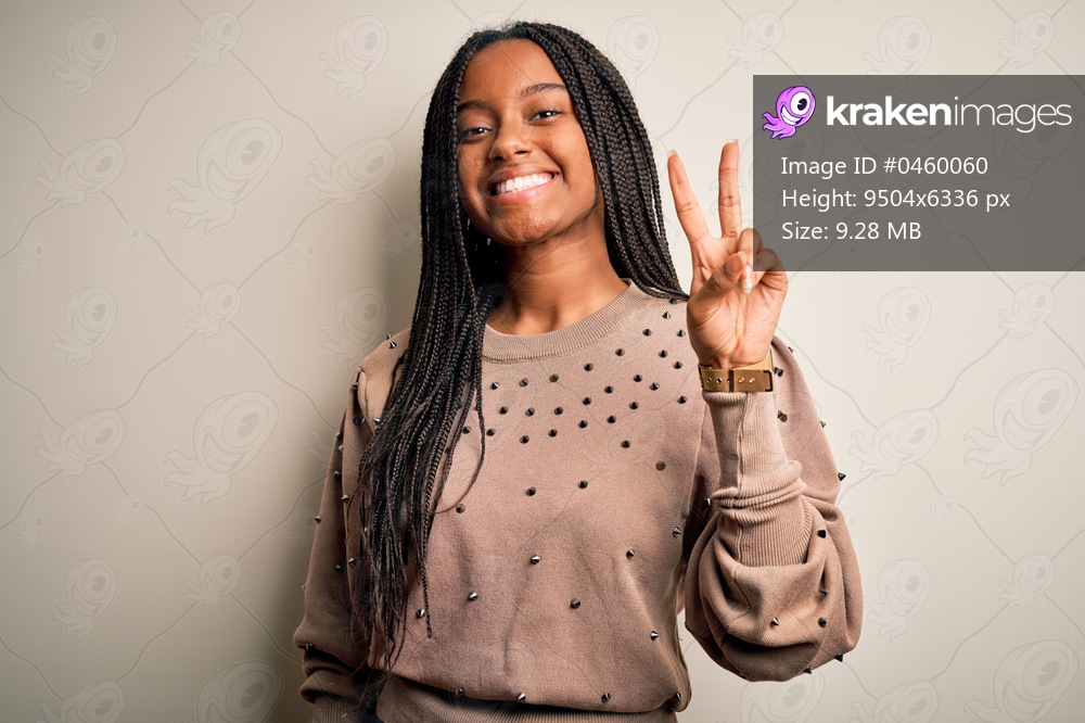 Young african american fashion woman standing casual over brown isolated background smiling with happy face winking at the camera doing victory sign. Number two.