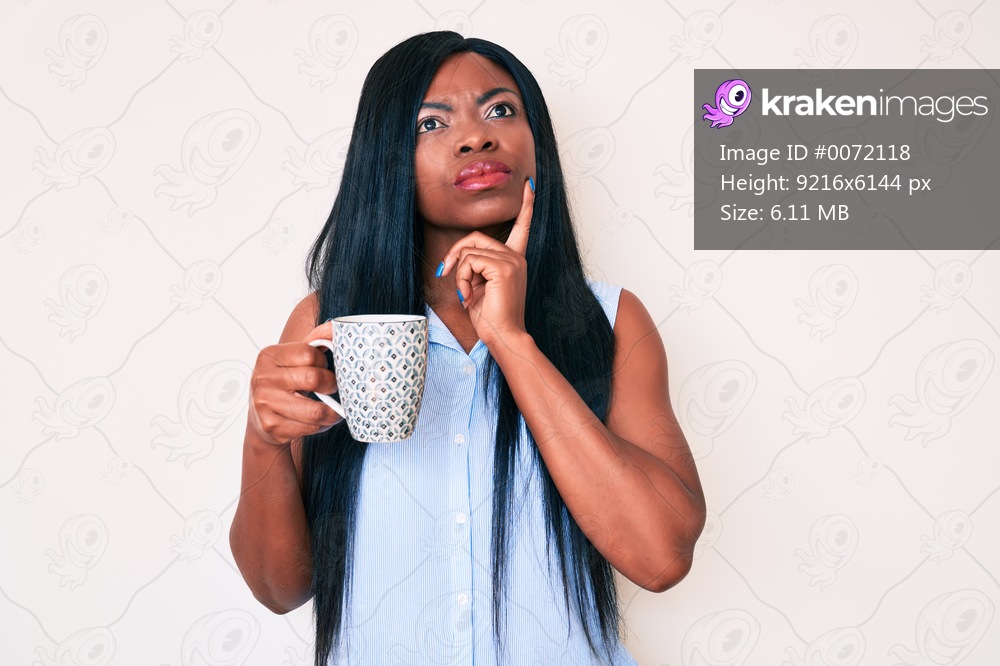 Young african american woman holding coffee serious face thinking about question with hand on chin, thoughtful about confusing idea 