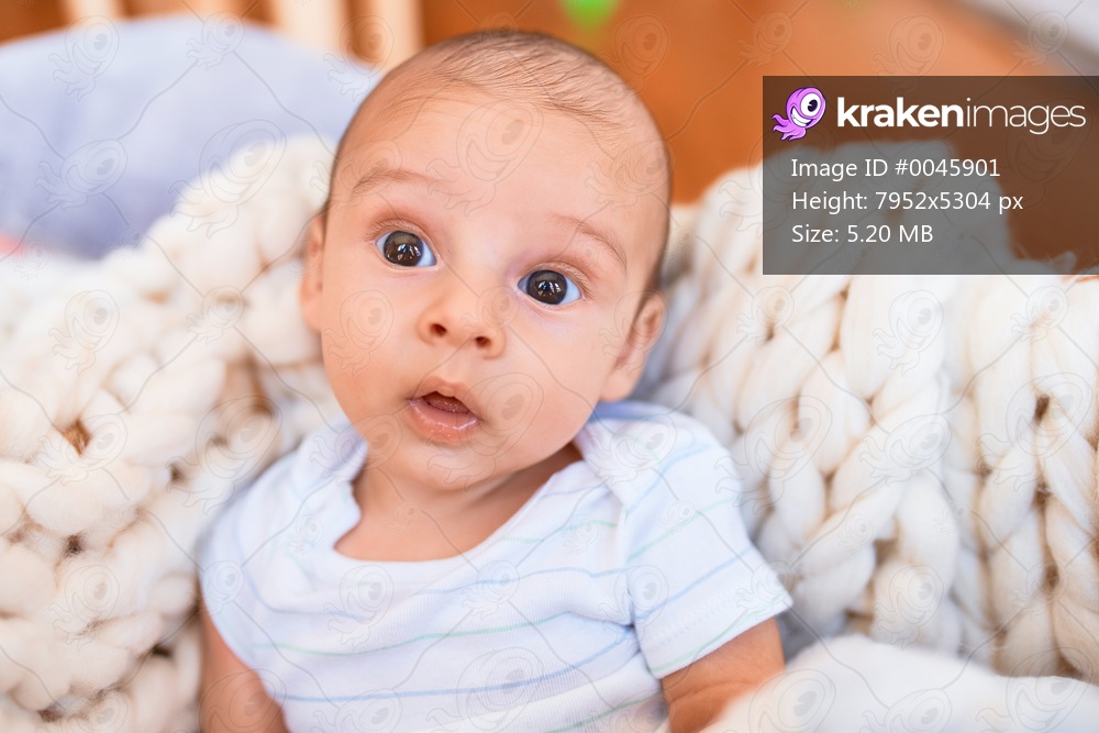 Adorable baby lying down over blanket on the floor at home. Newborn relaxing and resting comfortable
