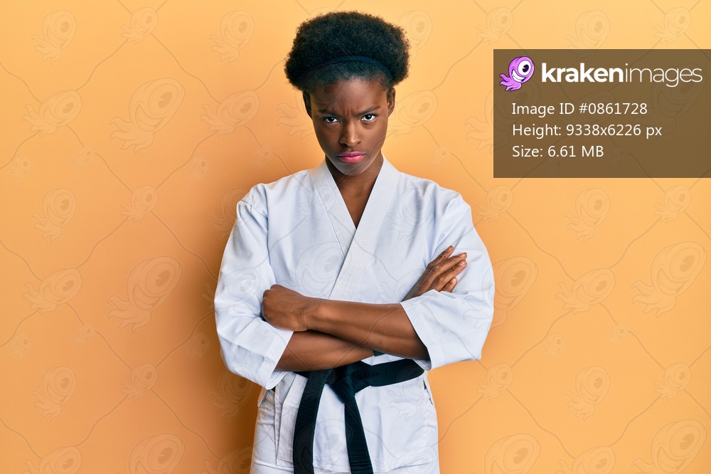 Young african american girl wearing karate kimono and black belt skeptic and nervous, disapproving expression on face with crossed arms. negative person. 