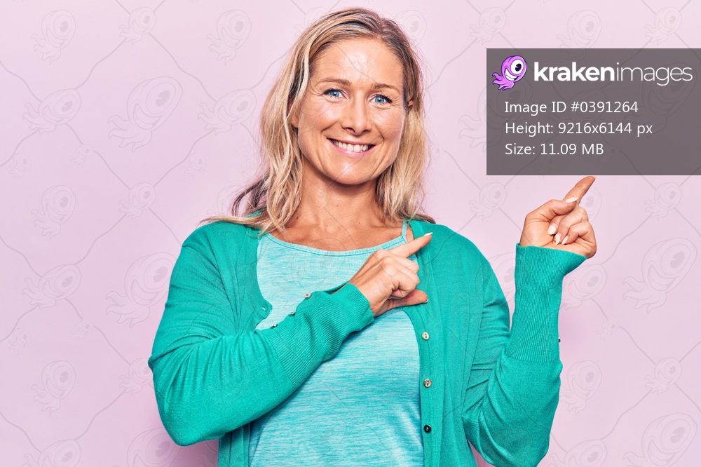 Middle age caucasian blonde woman wearing casual clothes smiling and looking at the camera pointing with two hands and fingers to the side. 