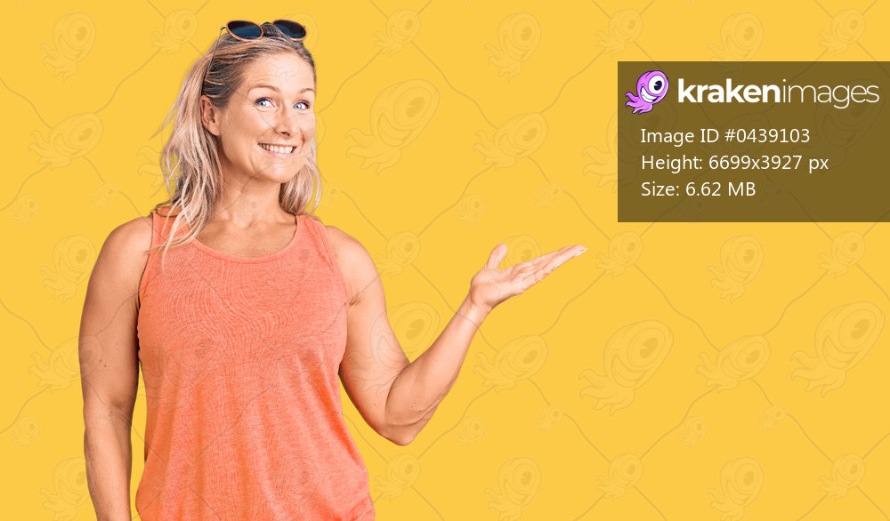 Middle age fit blonde woman wearing casual summer clothes and sunglasses smiling cheerful presenting and pointing with palm of hand looking at the camera. 