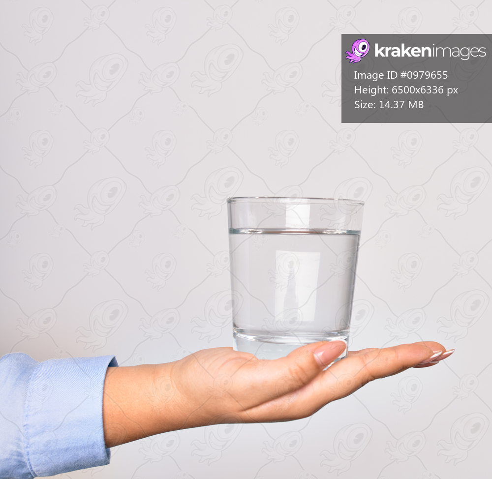 Hand of caucasian young woman holding glass of water over isolated white background