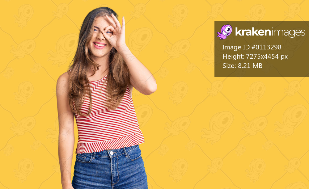 Beautiful caucasian young woman wearing casual clothes doing ok gesture with hand smiling, eye looking through fingers with happy face. 