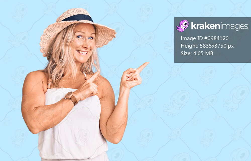 Middle age fit blonde woman wearing summer hat smiling and looking at the camera pointing with two hands and fingers to the side. 