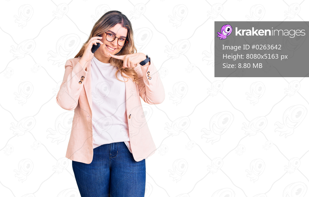 Young caucasian woman having conversation talking on the smartphone smiling happy pointing with hand and finger 