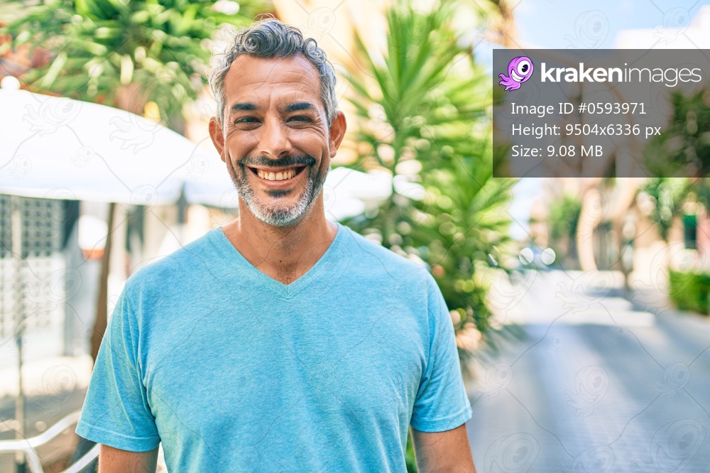 Middle age grey-haired man smiling happy walking at street of city.