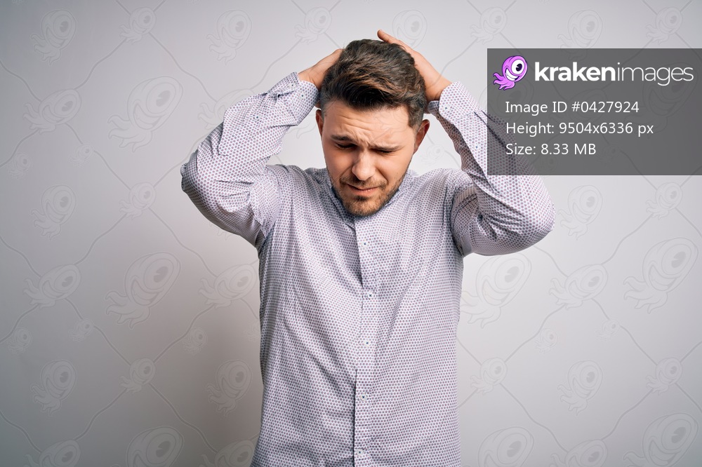 Young business man with blue eyes standing over isolated background suffering from headache desperate and stressed because pain and migraine. Hands on head.