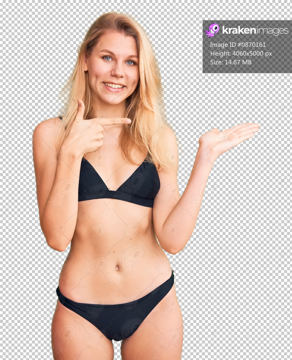 Young beautiful blonde woman wearing bikini amazed and smiling to the camera while presenting with hand and pointing with finger.