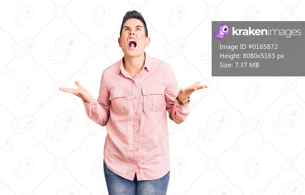Young woman with short hair wearing casual clothes crazy and mad shouting and yelling with aggressive expression and arms raised. frustration concept. 