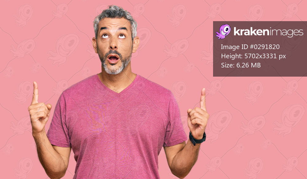 Middle age grey-haired man wearing casual clothes amazed and surprised looking up and pointing with fingers and raised arms. 