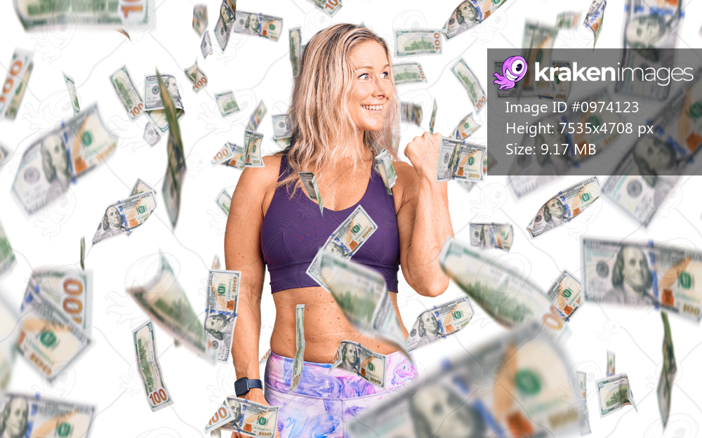 Middle age fit blonde woman wearing sportswear smiling with happy face looking and pointing to the side with thumb up.