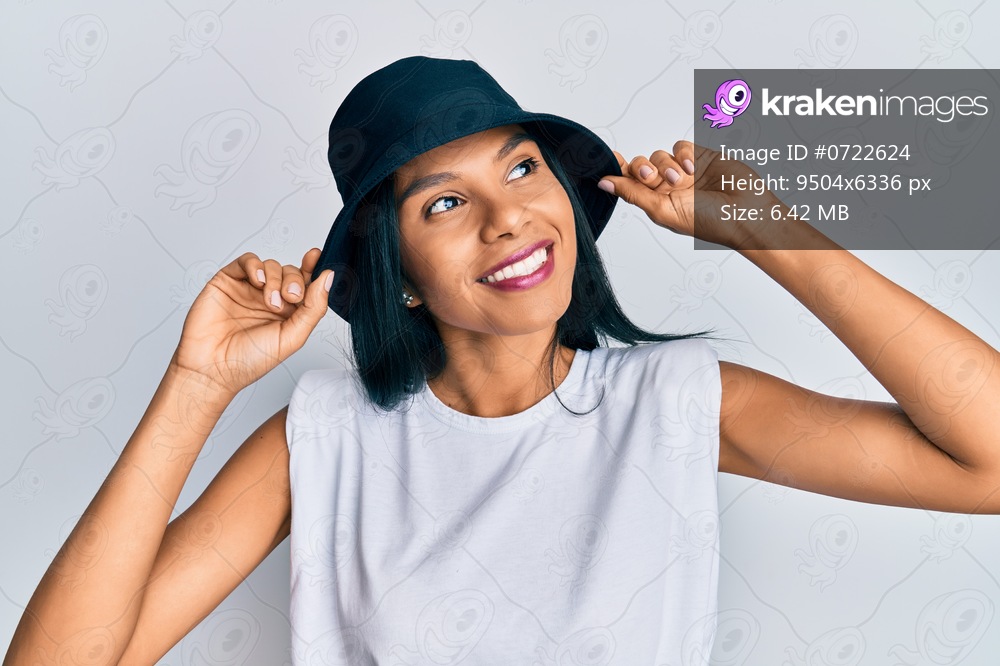 Young african american woman wearing fashion hat smiling looking to the side and staring away thinking. 