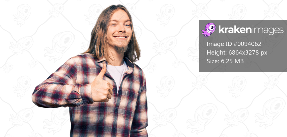 Handsome caucasian man with long hair wearing hipster shirt doing happy thumbs up gesture with hand. approving expression looking at the camera showing success. 