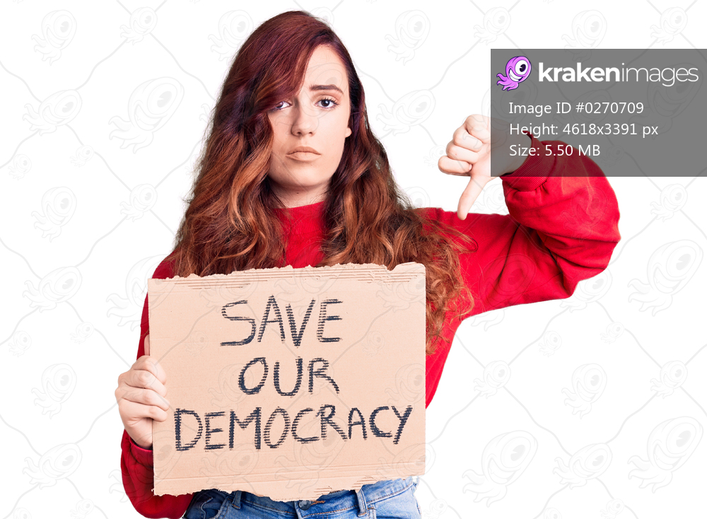 Young beautiful woman holding save our democracy protest banner with angry face, negative sign showing dislike with thumbs down, rejection concept 